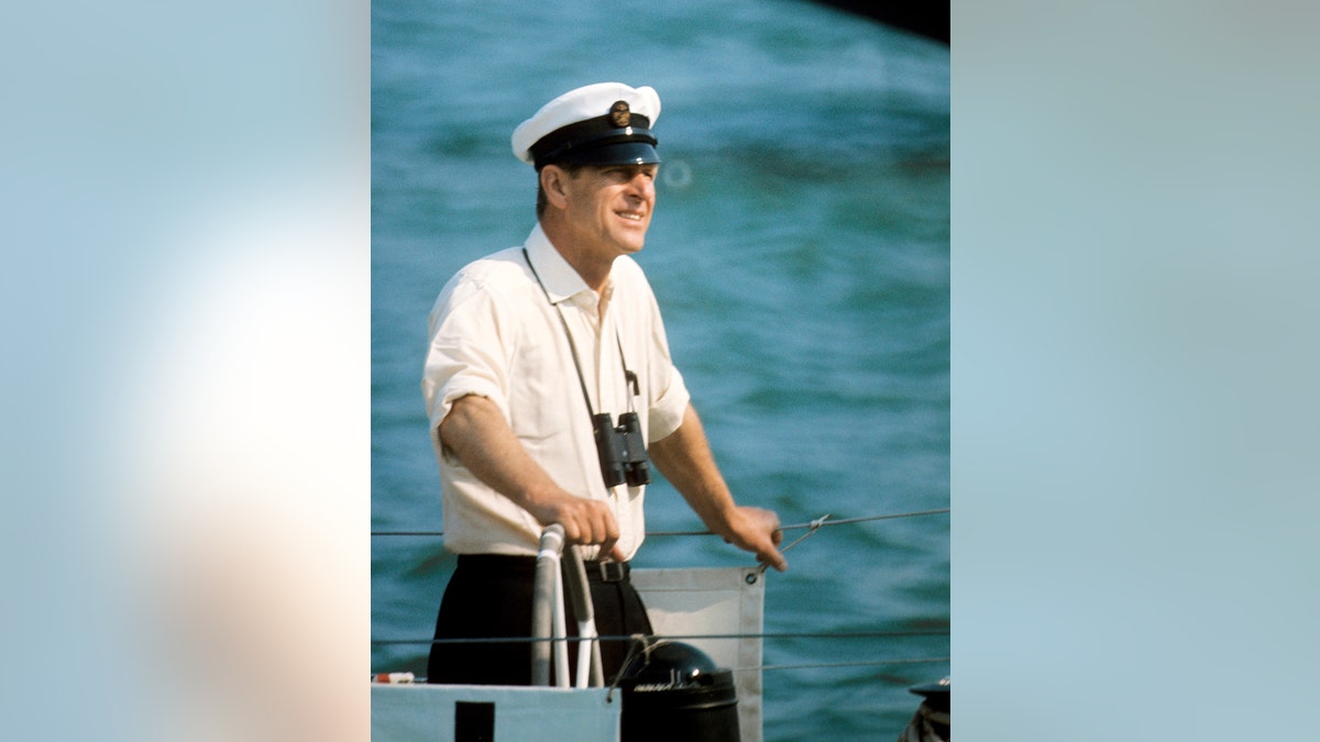 Prince Philip wearing a white shirt and a sailor's hat smiling.