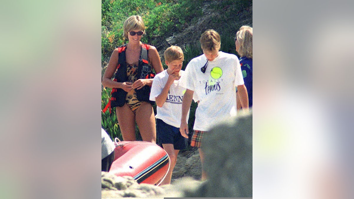 Princess Diana smiling in a leopard swimsuit walking next to Prince Harry and Prince William.