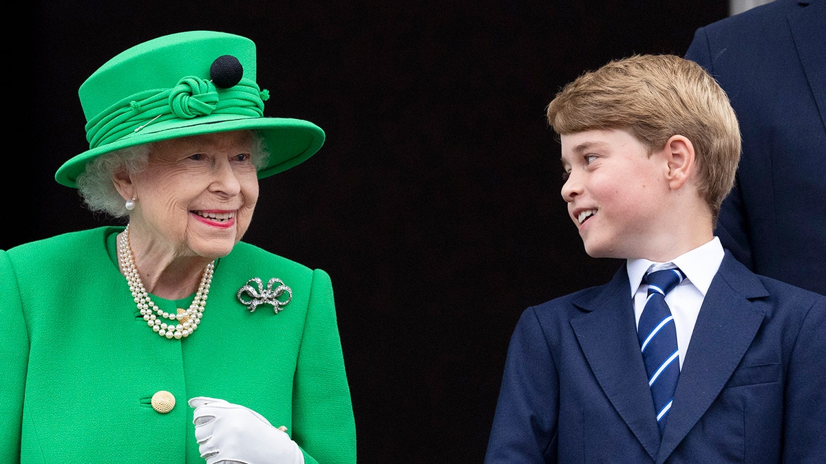 Prince George in a blue suit smiles to Queen Elizabeth