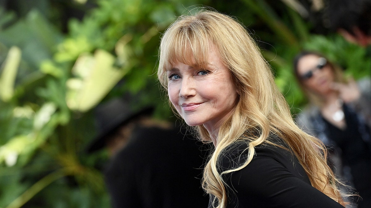 Rebecca De Mornay wearing a black dress and smiling.