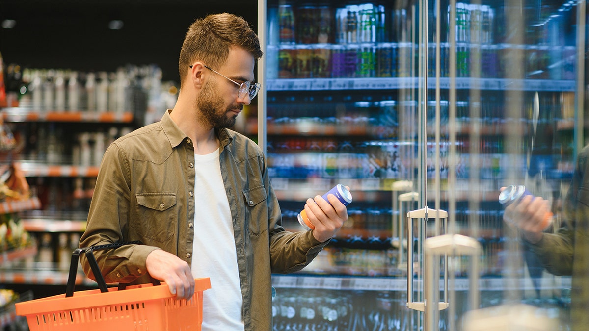Man observing drink in grocery store