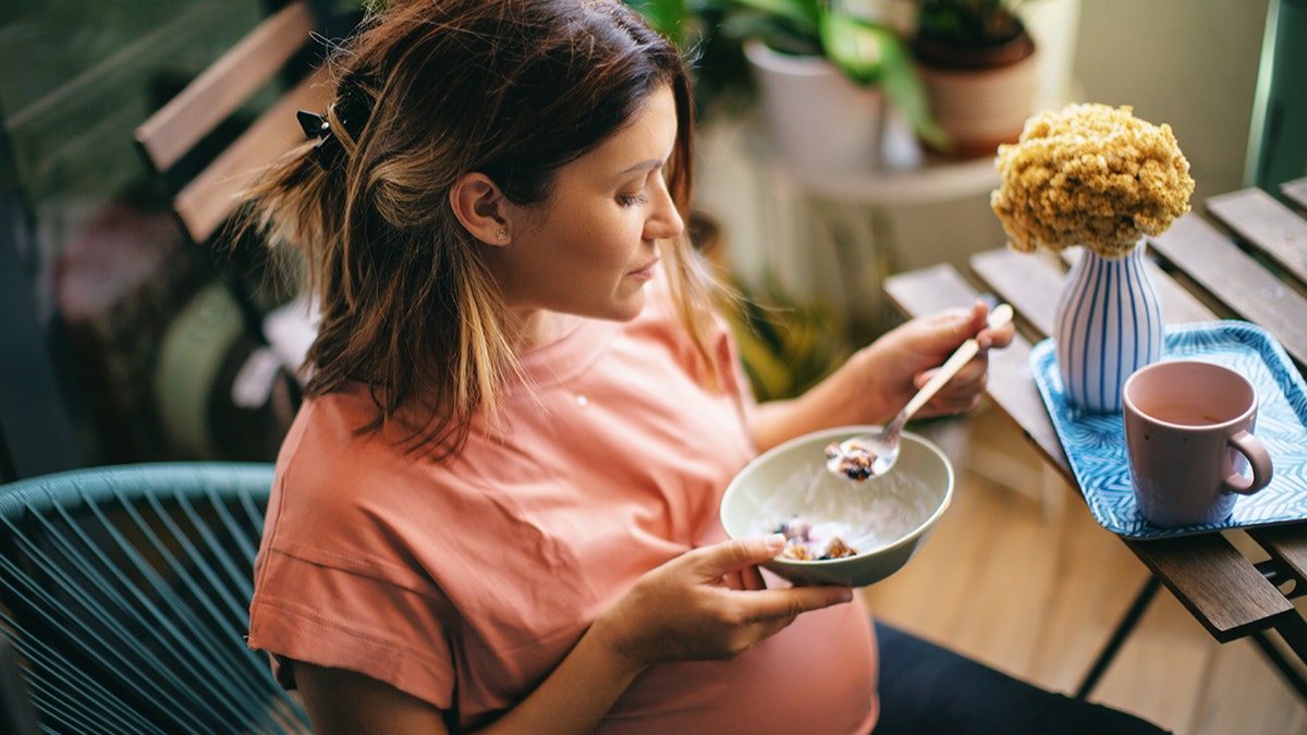 Pregnant woman smiling and eating