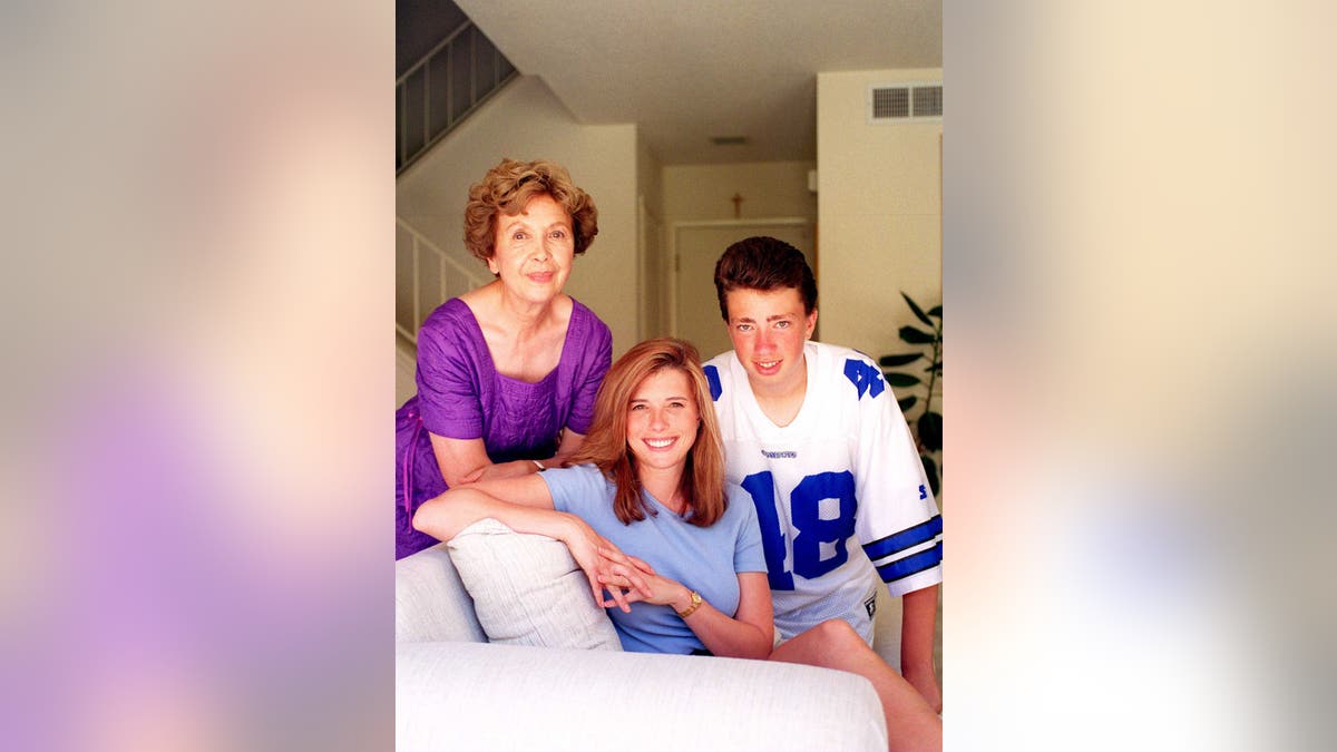 Roxanne Tunis with her children wearing a purple dress and posing in their home for a photo.