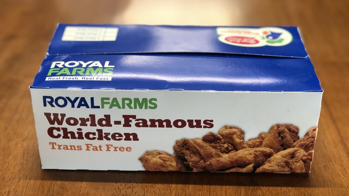 A box of royal farms sits on a table of fried chickens.