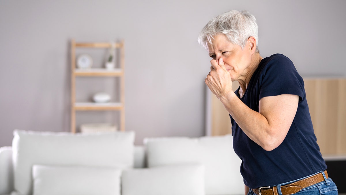 Woman holding nose due to smell.