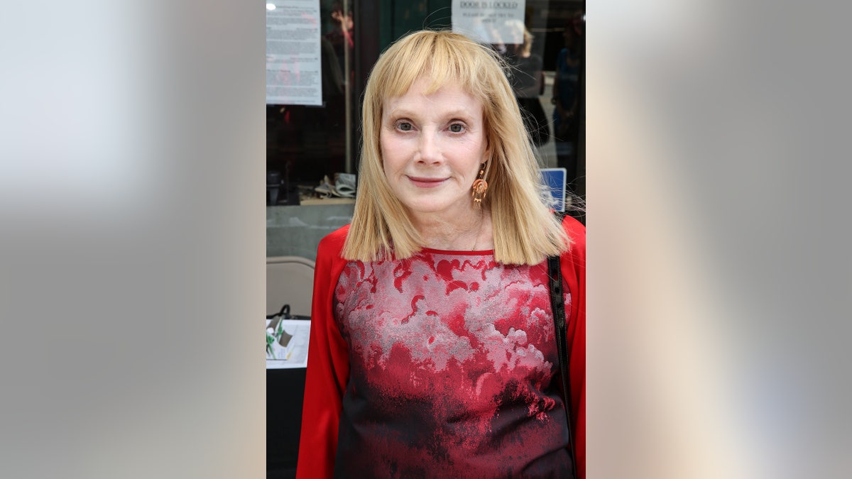 Sondra Locke wearing a red and white blouse.