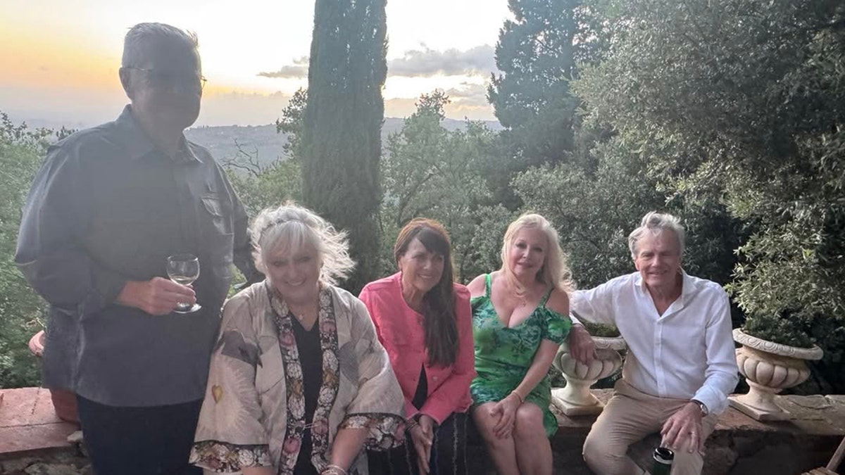 El elenco del sonido de la música sentados juntos y compartiendo una botella de vino.