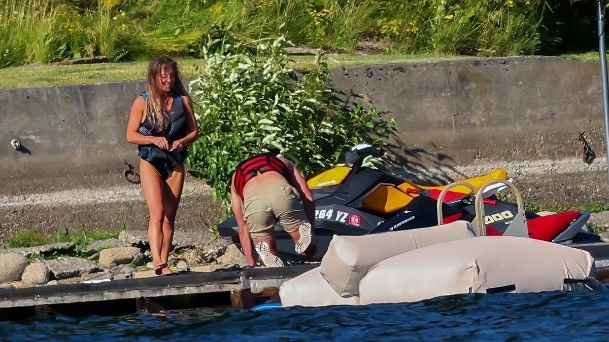 Sydney Sweeney walks on to a dock near a lake house.