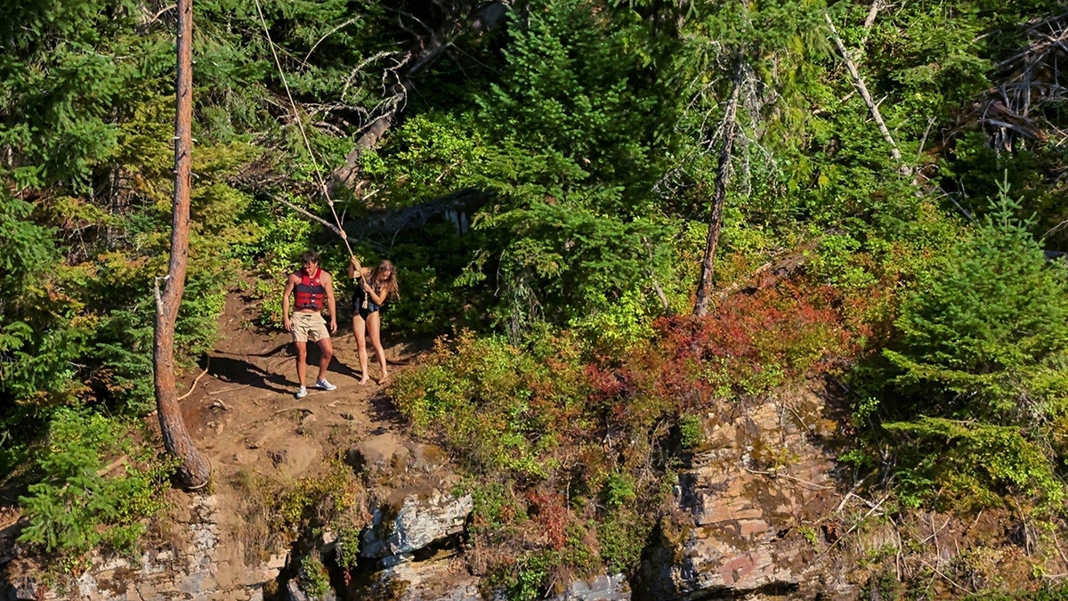Sydney Sweeney hikes along a lake with a mystery man