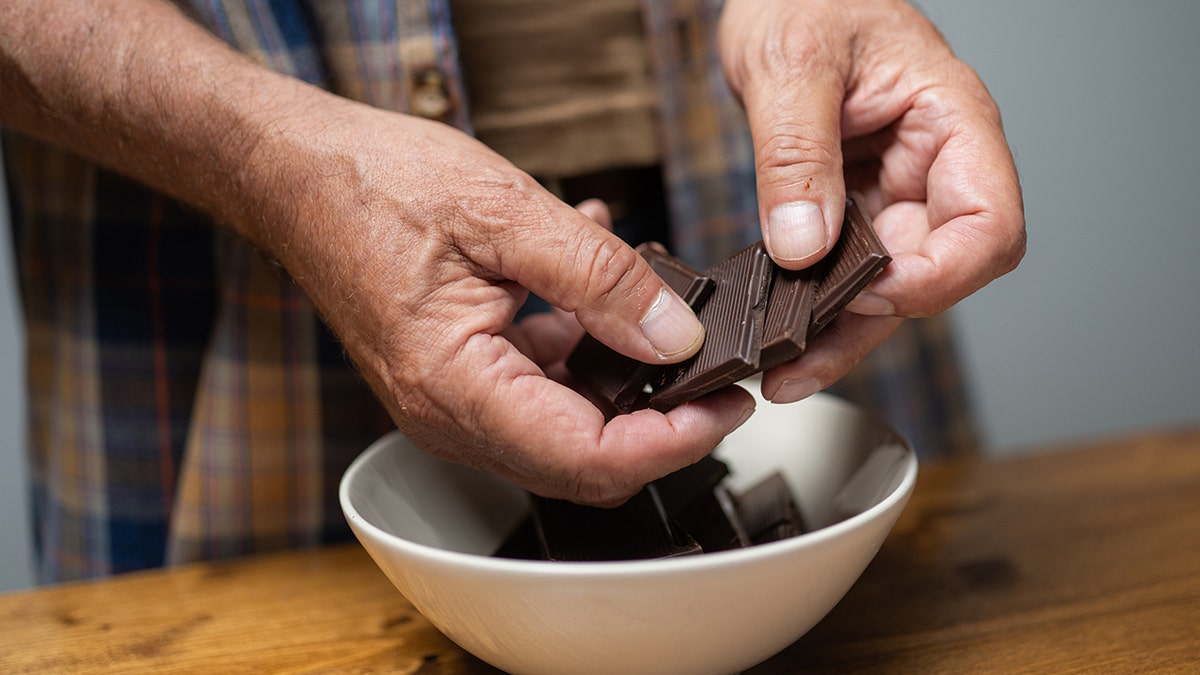 Man cracking a bar of dark chocolate