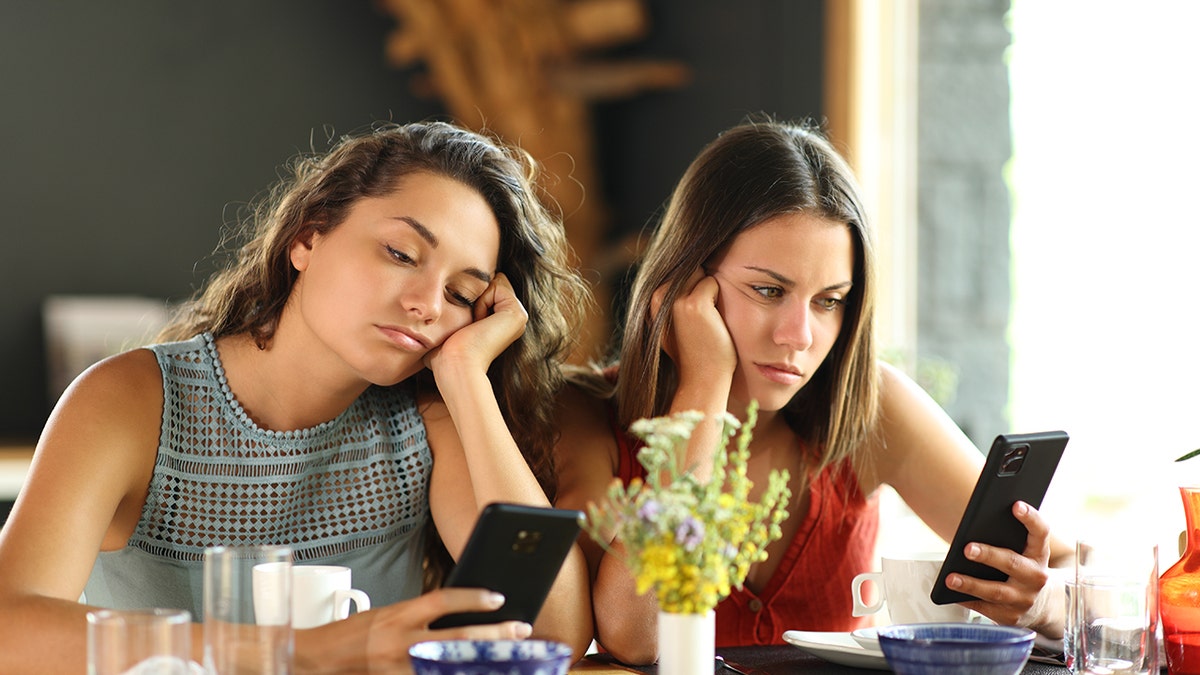 Upset Gen Z girls looking at their phones