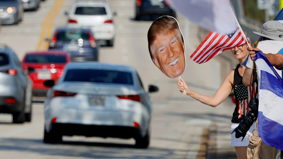 A cardboard cutout of Former President Donald Trump's look is held by a protagonist on Southern Boulevard successful West Palm Beach, Florida.