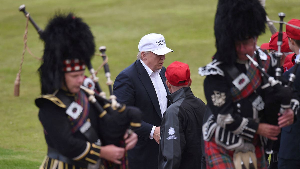 Trump stands by bagpipers in Scotland.