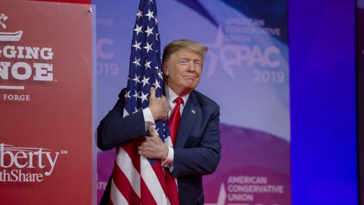 NATIONAL HARBOR, MD - MARCH 02: (AFP OUT) U.S. President Donald Trump hugs the U.S. flag during CPAC 2019 on March 02, 2019 in National Harbor, Maryland. The American Conservative Union hosts the annual Conservative Political Action Conference to discuss conservative agenda. (Photo by Tasos Katopodis/Getty Images)