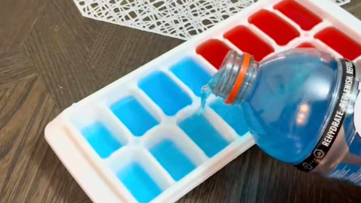 TikToker pouring bluish Gatorade into crystal cube tray, half of which is filled pinch reddish Gatorade.