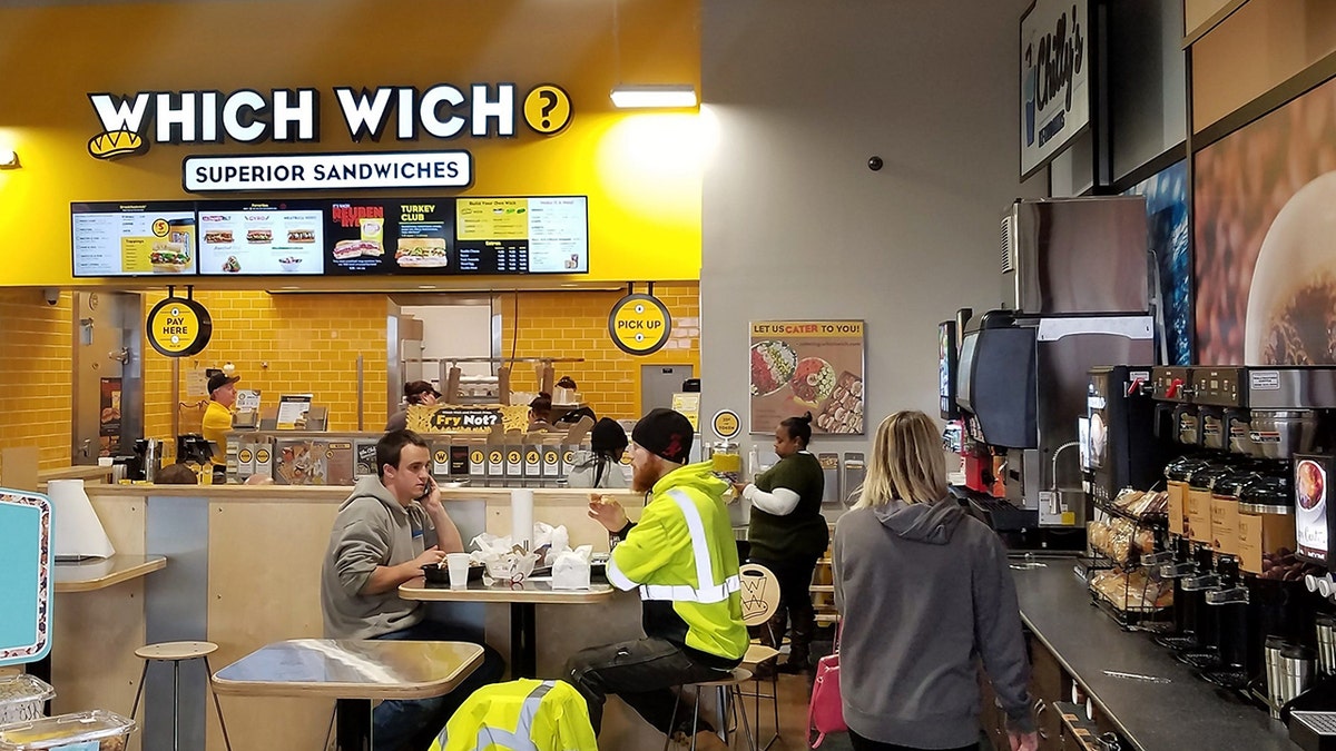 A Which Wich Superior Sandwiches stand is seen inside a convenience store.