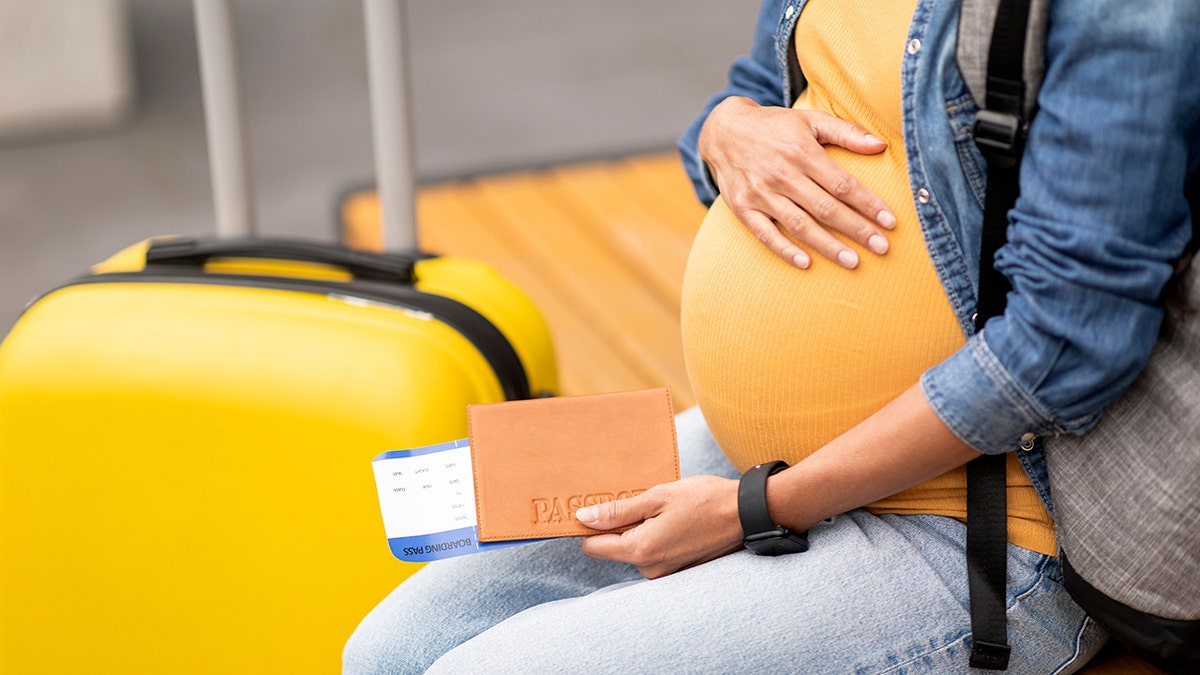 pregnant flight passenger at airport with luggage