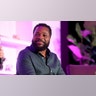 Malcolm-Jamal Warner wears a black shirt on stage during panel discussion.