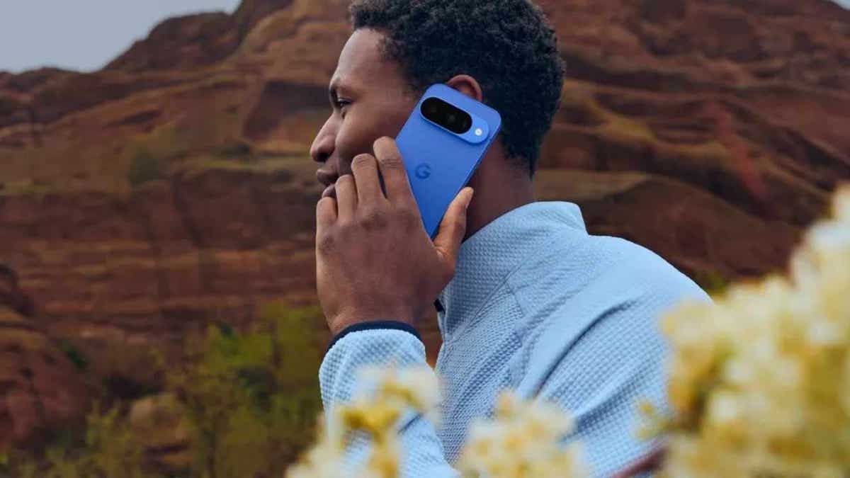 A man holds a blue Google Pixel 10 smartphone up to his ear.