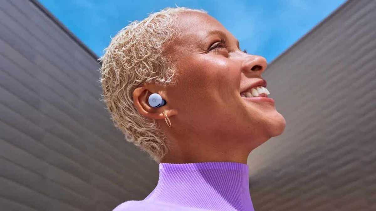 A woman smiles and looks upward as she wears Google's Pixel Buds 2a.