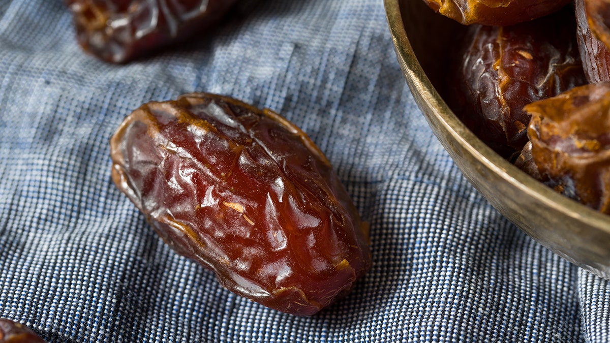 Organic Red Medjool datums, kas redzams uz galdauta blakus bļodiņai datumu