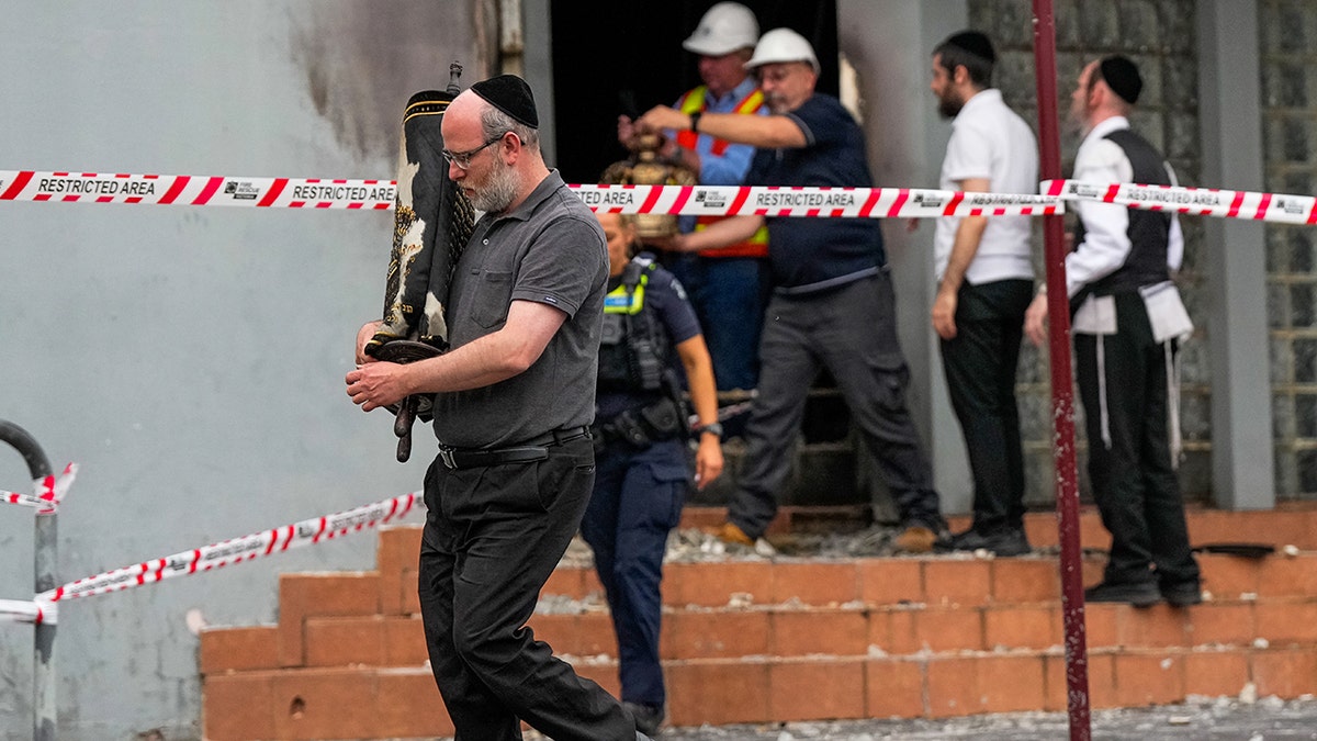 The man carries the Torah to scroll through a synagogue which has been attacked