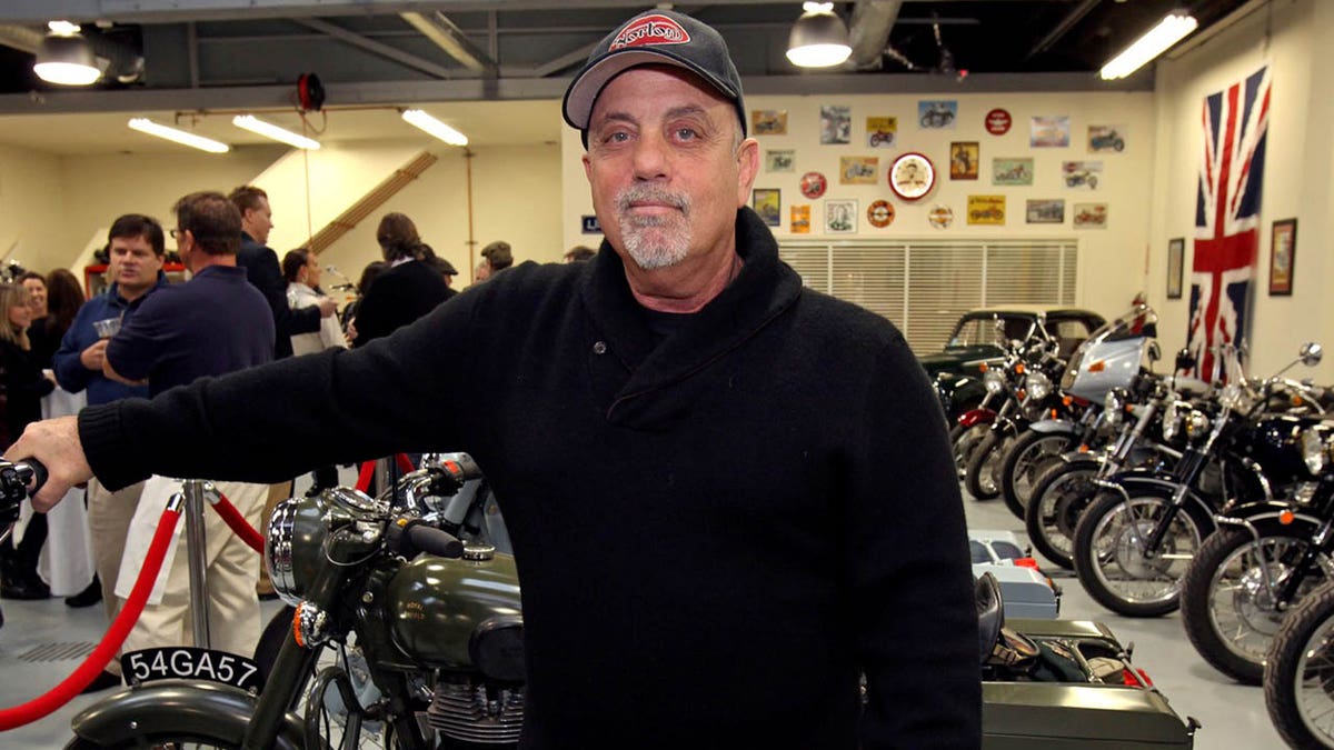 Billy Joel is pictured standing inside his motorcycle shop. 