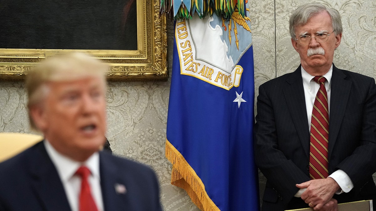 White House National Security Advisor John Bolton (R) listens to U.S. President Donald Trump as he and Dutch Prime Minister Mark Rutte talk to reporters in the Oval Office at the White House July 18, 2019