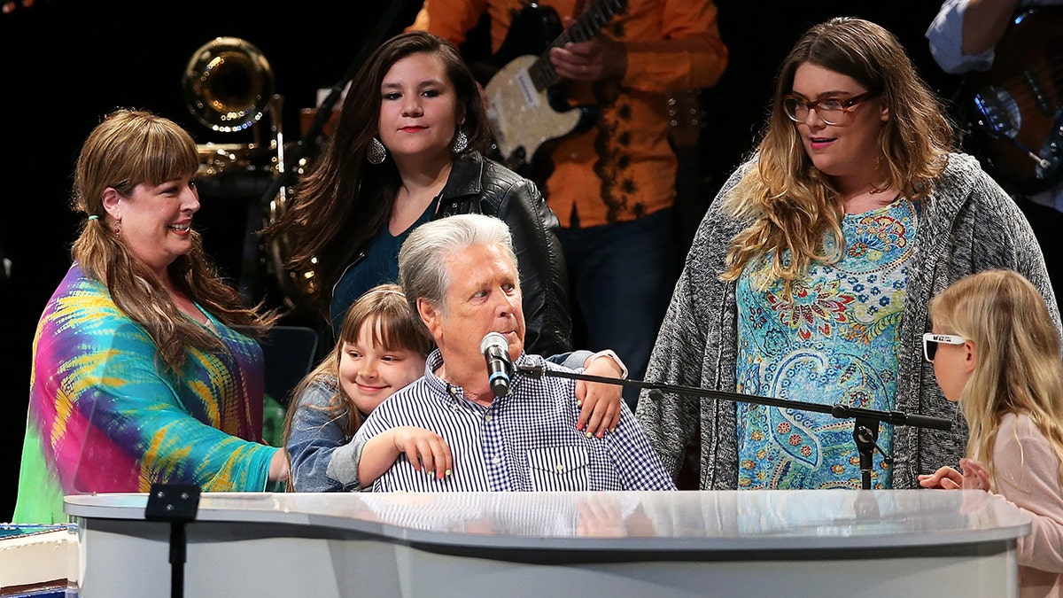 布萊恩·威爾遜（Brian Wilson）在舞台上表演，周圍是他的家人。
