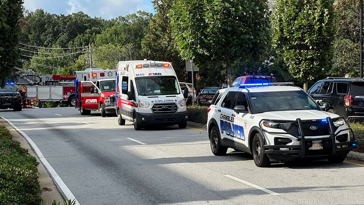 Veículos de emergência alinhados em uma estrada na cena de tiro