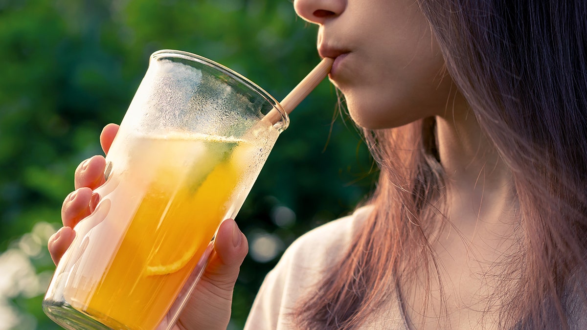 Girl drinks from a glass with summer cocktail inside