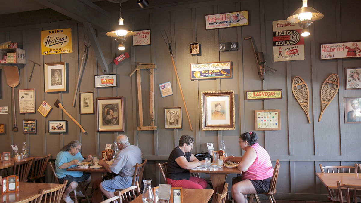 Customers of beloved Cracker Barrel slam the restaurant remodels on social media 1 Cracker Barrel customers eat next to an interior wall with antiquities on it.