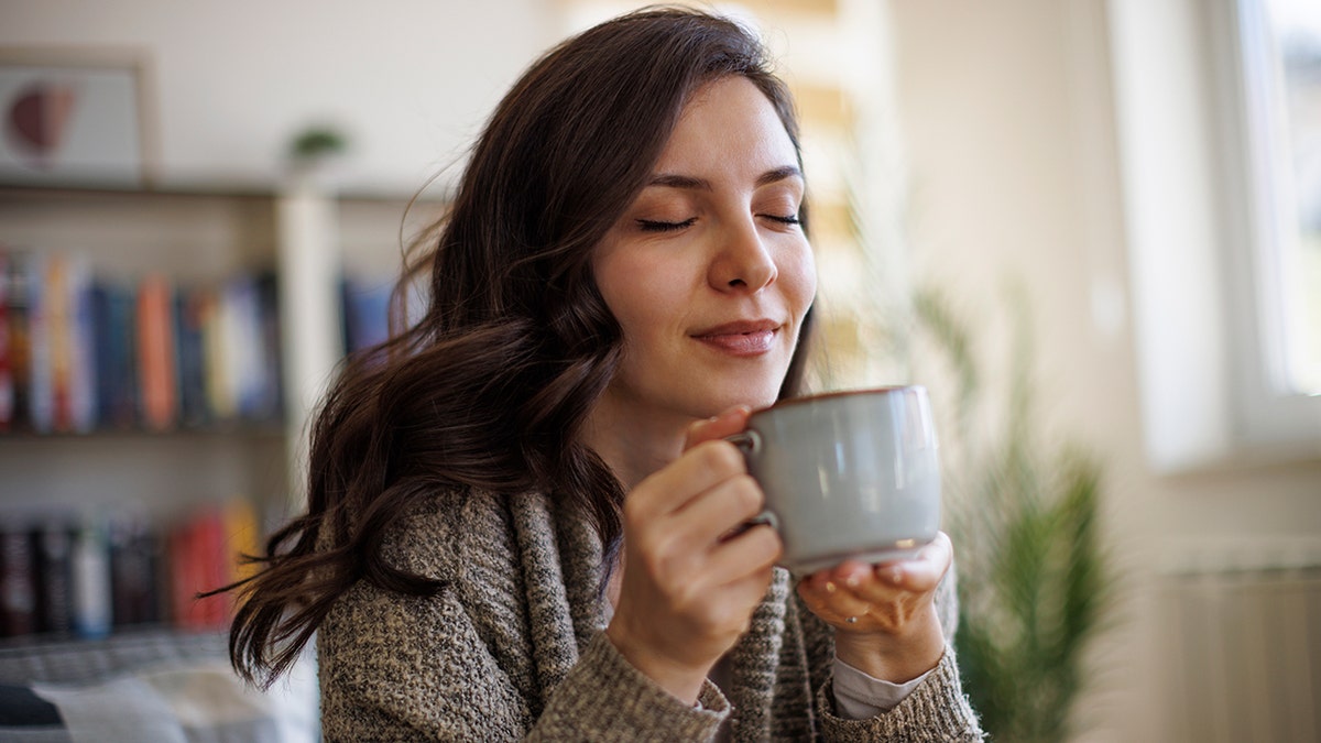 Woman smiling while about to drink tea.