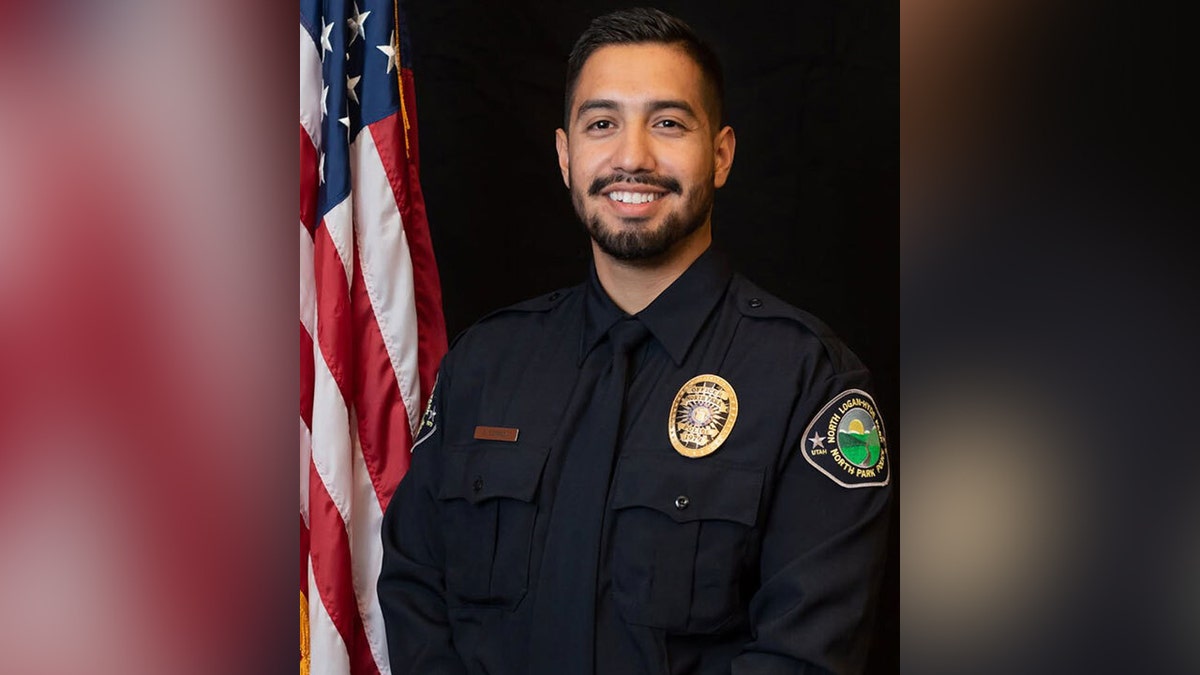 Officer Eric Estrada posing in uniform in front on American flag