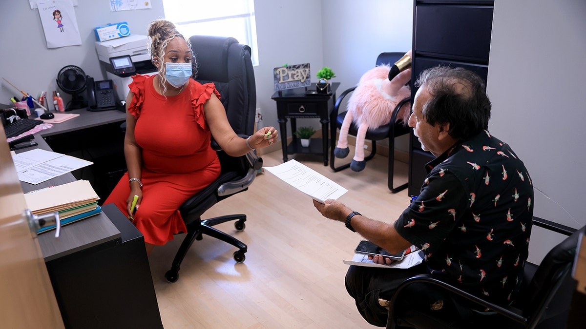 Alicia Lester, case manager and services coordinator, Helry Pedoff helps to fill a Medicaid and an application of food coupons at Lifenet4Families Center on May 14, 2025 in Lauderhill, Florida.