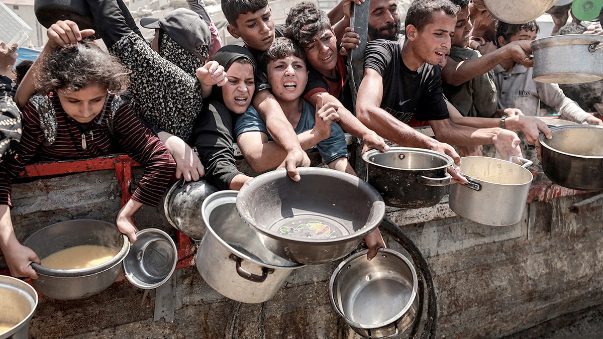 alestinians, including children, line up for hot meals distributed by a charity in Gaza City on July 30, 2025.
