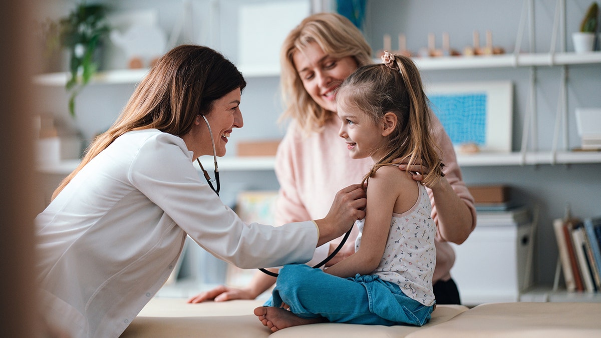 pediatrician examines a girl with her mother
