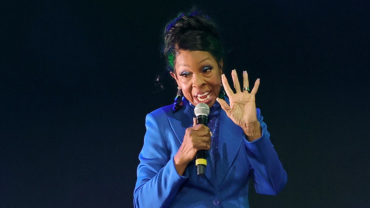 Gladys Knight sings on stage wearing a blue suit.