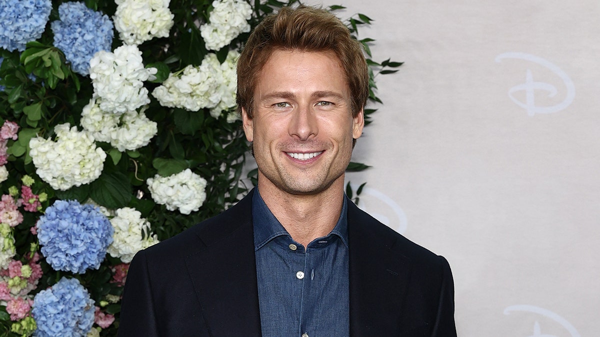 Glen Powell smiling at an event