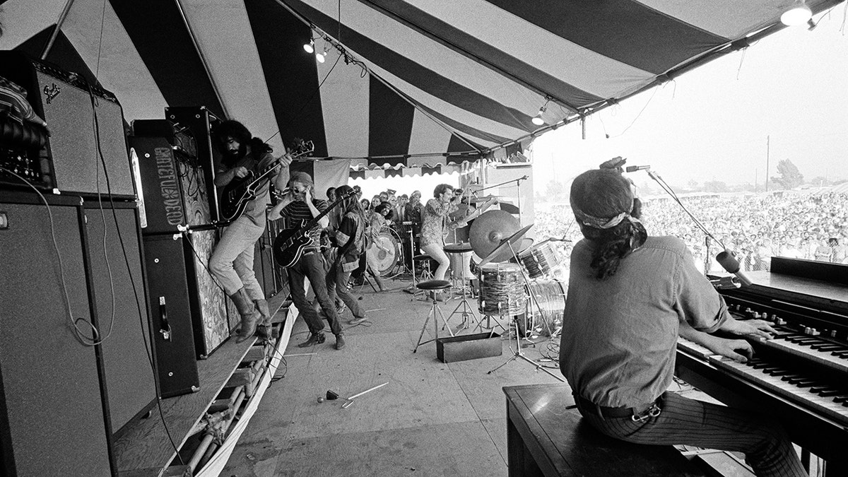 Jim Marshall photographing backstage as the Grateful Dead play on stage.