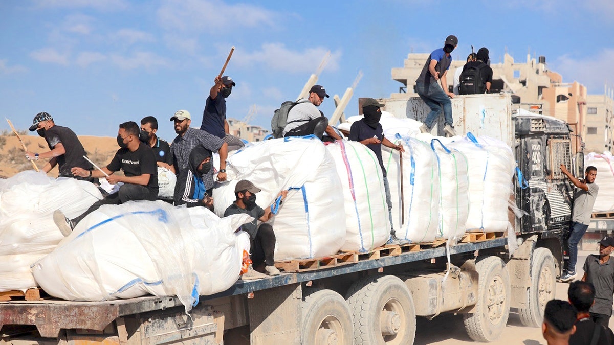 Hamas terrorists carrying clubs and firearms secure humanitarian aid trucks in the northern Gaza area of Jabaliya on June. 25