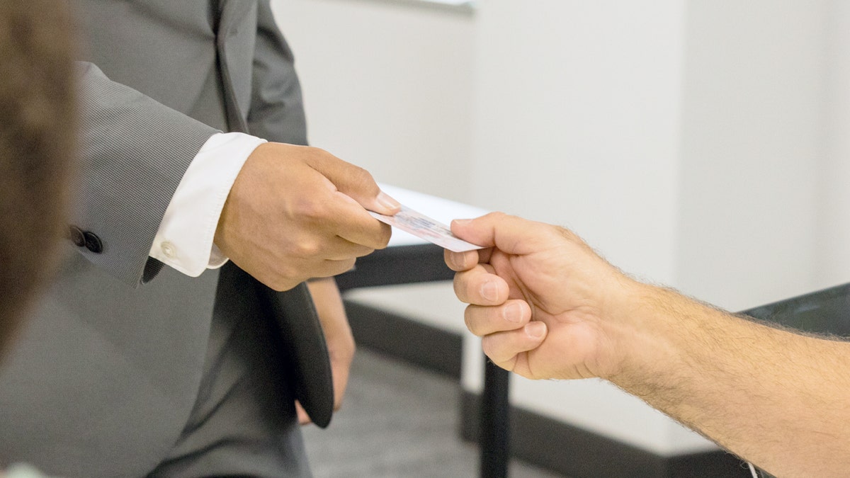 A man hands over an ID to a volunteer