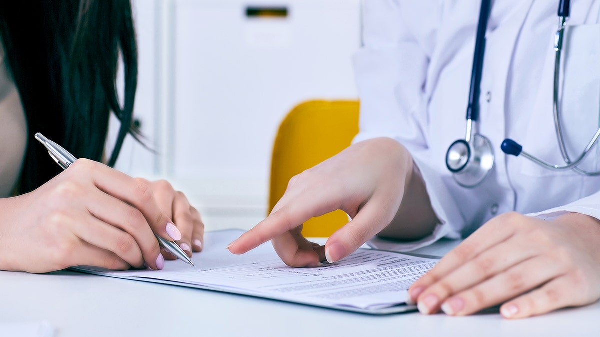 Patient and doctor who review La Paperasse, only the hands are shown