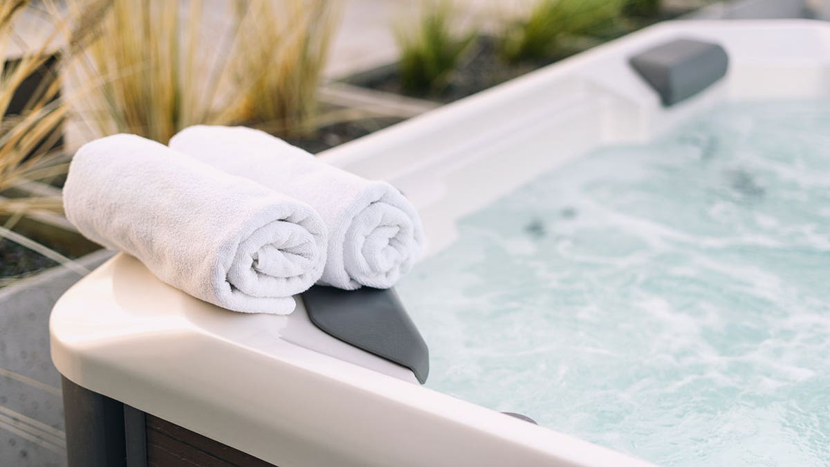 white towels placed on the edge of a hot tub with bubbling water