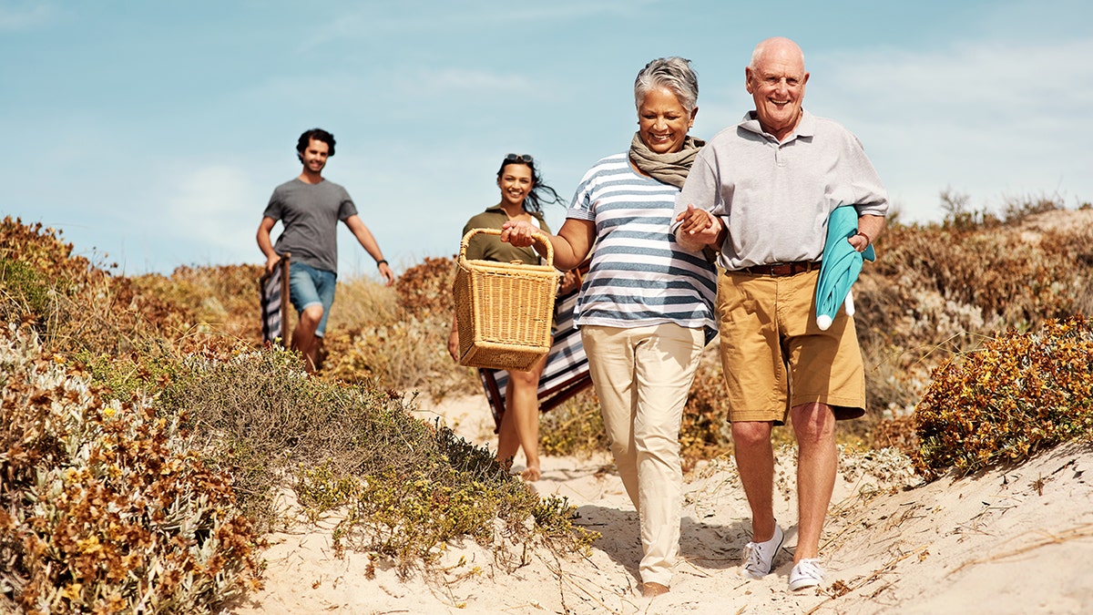 A husband behind the wife and his wife on the family beach vacation, indicating tension on the importance of every trip