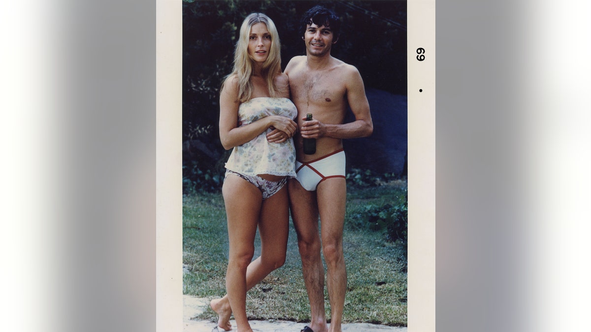 Sharon Tate and Jay Sebring in skimpy swimsuits by the pool smiling.