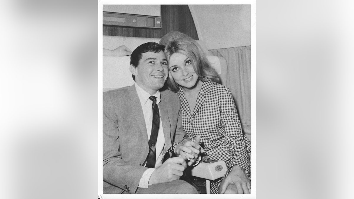 Jay Sebring and Sharon Tate leaning on each other and smiling.