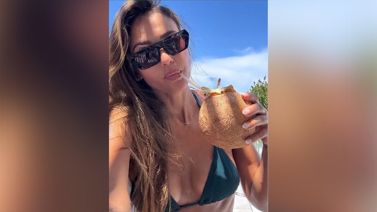 Jessica Alba sipping out of a coconut while outside in sunglasses and a green bikini.