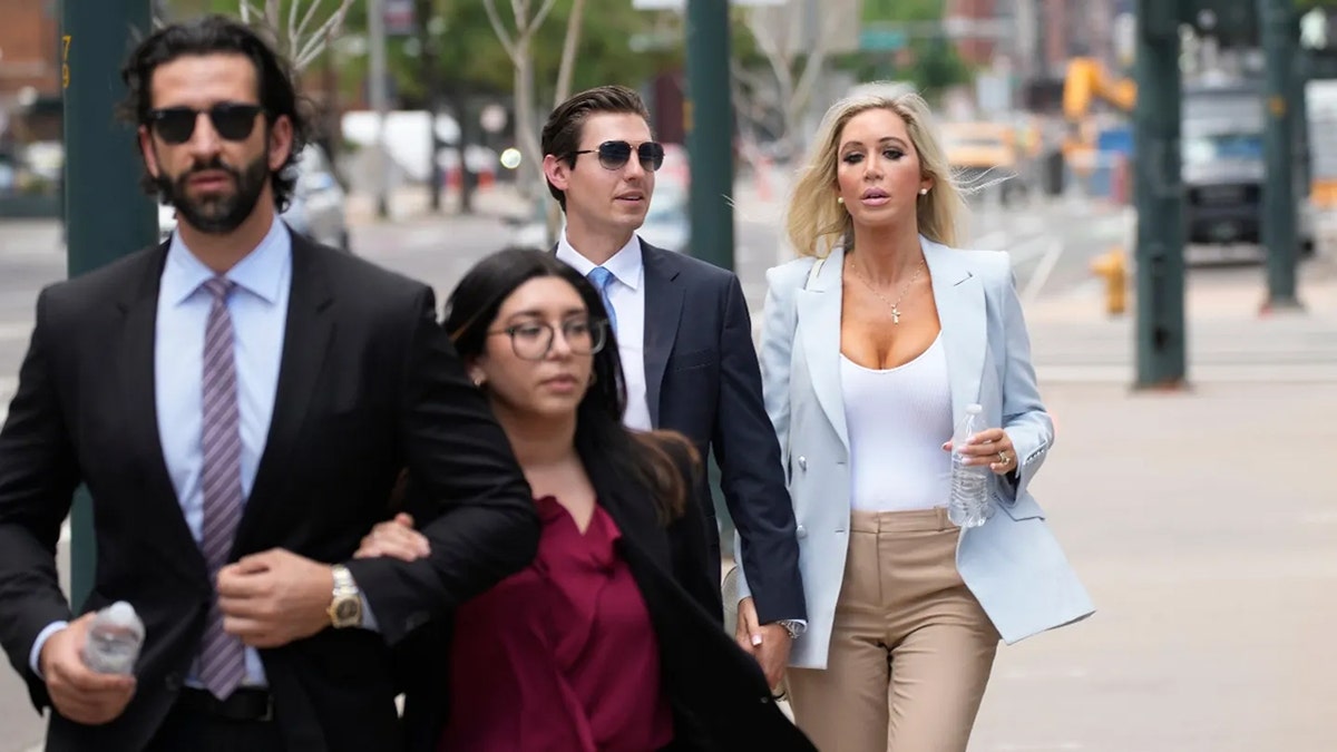 Larry Rudolph's children in suits and formal wear walking outdoors looking upset as they head to court.