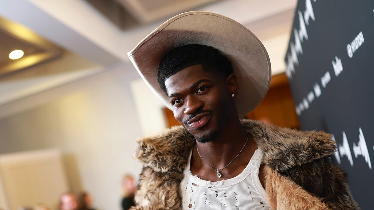 Lil Nas X wears furry coat and cowboy hat.